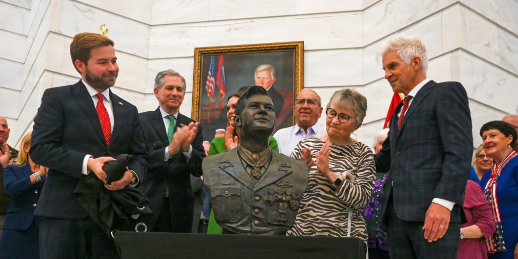 Arkansas Secretary of State Cole Juster, U.S. Rep. French Hill and members of the family of Maurice “Footsie” Britt applaud after a bust of Britt was unveiled during a ceremony at the Arkansas State Capitol on July 7. It was sculpted by artist Kevin Kresse (right). Photo: Kameron Green/ Little Rock Air Force Base