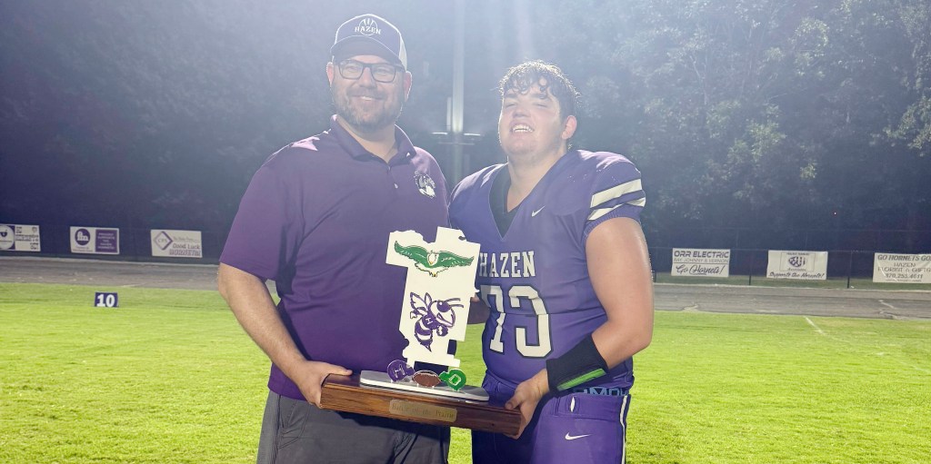 Hazen School Board member Cody Snider and his son Luke Snider hold the Battle of the Prairie trophy after the Hornets beat Des Arc on Friday night.